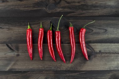 Ahşap masa üzerinde altı kırmızı biber. Üstten Görünüm