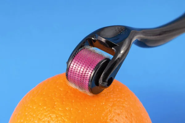Rullo dermico per micro terapia medica con aghi con arancia . — Foto Stock