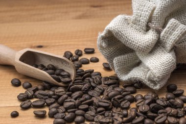 Kahve çekirdekleri ile ahşap kepçe ve ahşap masa üstünde keten çanta