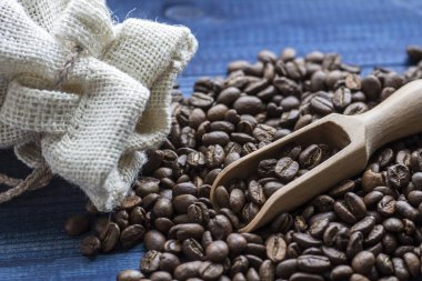 Kahve çekirdekleri ile ahşap kepçe ve ahşap masa üstünde keten çanta