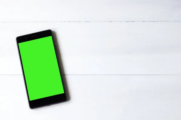 在木桌上的绿色屏幕智能手机 — 图库照片