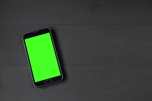 Smart phone with green screen on wooden desk — Stock Photo, Image