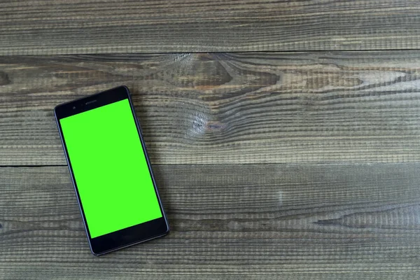 Smart phone with green screen on wooden desk — Stock Photo, Image
