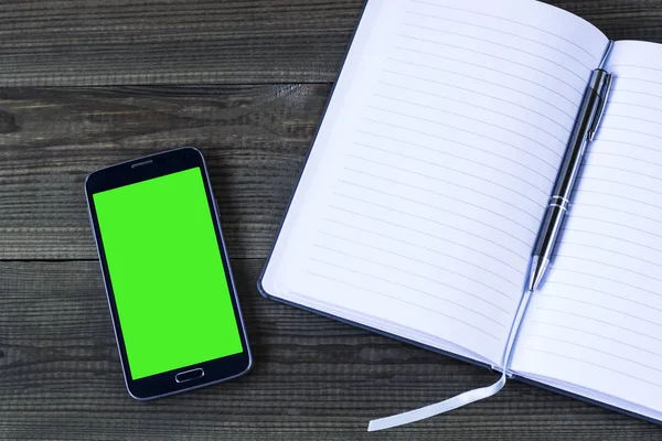 Smart phone with green screen with notepad — Stock Photo, Image