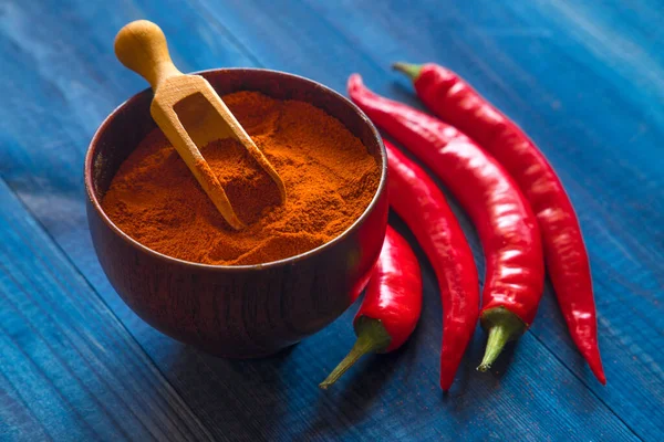 Peperoni peppers with chili powder on blue table