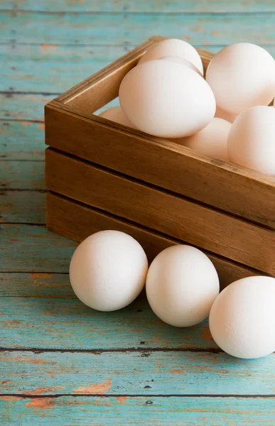 Caixa de madeira de ovos frescos em uma prancha de madeira placa de fundo — Fotografia de Stock