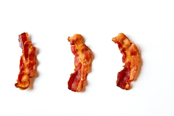 Três fatias de bacon isolado em um fundo branco — Fotografia de Stock