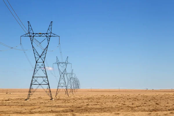 Rij hoog Voltage Power Lines onder een blauwe hemel — Stockfoto