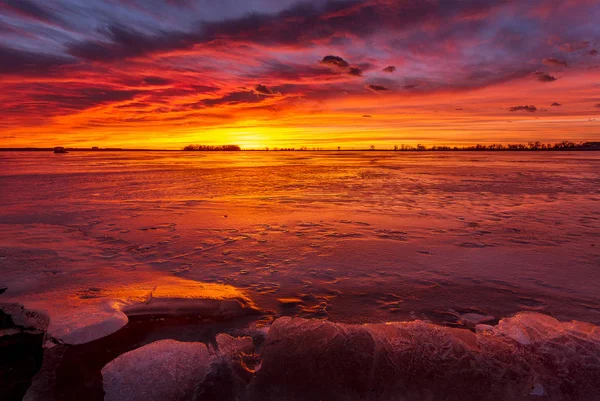 Colorful Sunrise or Sunset on a frozen lake with rocks in the fo — Stock Photo, Image