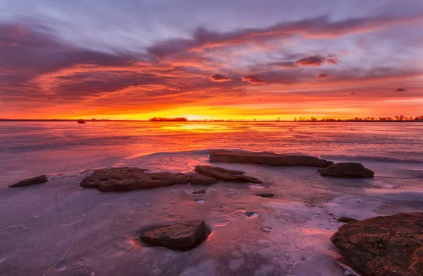 Kleurrijke zonsopgang of zonsondergang op een bevroren meer met stenen in de fo — Stockfoto