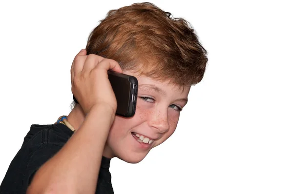 Niño sonriendo mientras habla en un teléfono celular — Foto de Stock