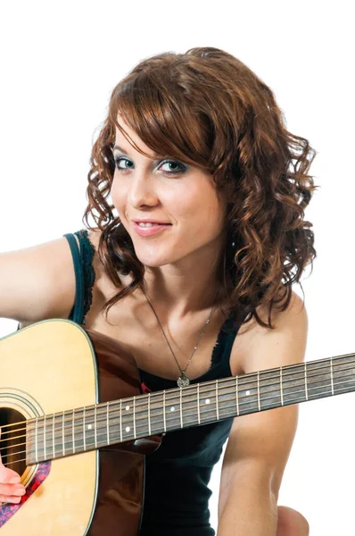 Piękna młoda brunetka uśmiecha się grając na gitarze. — Zdjęcie stockowe