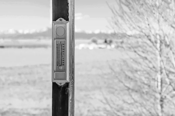 Black and white photo of an analog thermometer mounted outside — Stock Photo, Image