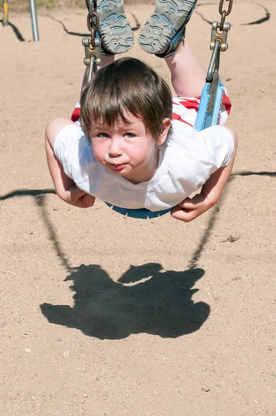 Cute little boy zbyt krótki siedzieć w większych huśtawkach — Zdjęcie stockowe