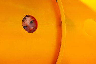 Küçük çocuklar oyun parkında plastik tüp tünelinde karşı karşıya.