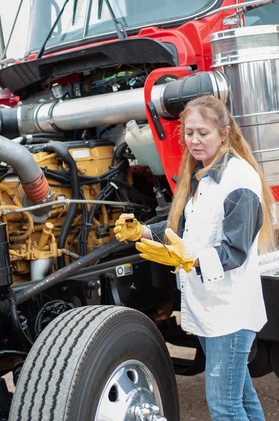 Vrouw vrachtwagenchauffeur controleren van het oliepeil op een grote vrachtwagen Rechtenvrije Stockfoto's
