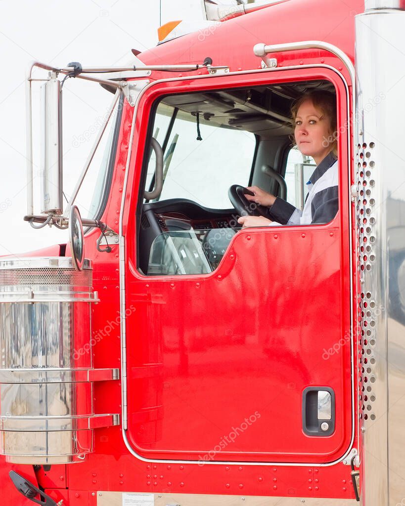Woman Truck Driver looking out the window while driving a big rig