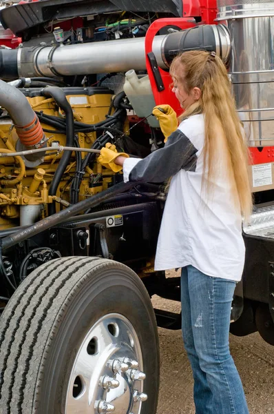 Femme chauffeur de camion vérifiant le niveau d'huile sur un gros camion Image En Vente