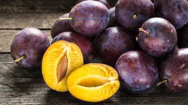 Fresh blue plums on wooden table — Stock Photo, Image