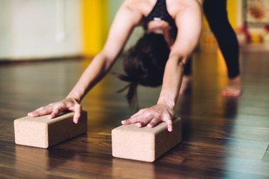 Yoga yapan bir kadın yoga için tuğla kullanıyor..