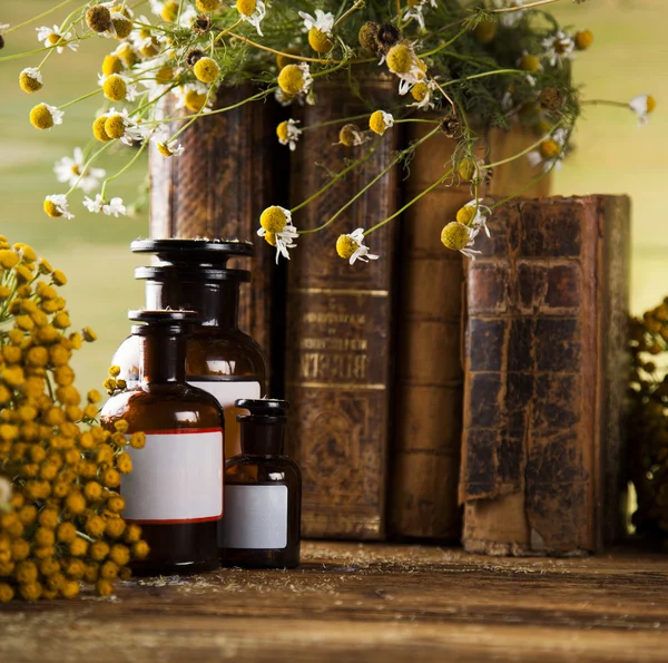 Kruidengeneeskunde en boeken over houten tafel — Stockfoto