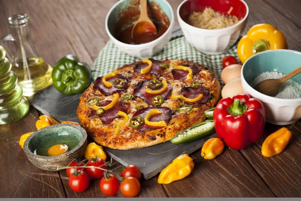 Pizza e ingredienti in tavola — Foto Stock