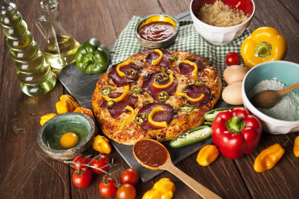 Pizza e ingredienti in tavola — Foto Stock