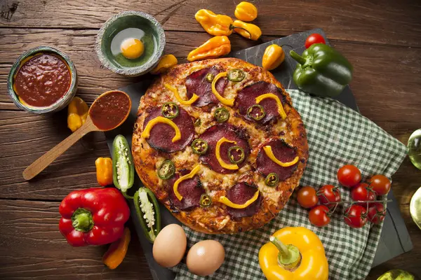 Pizza en ingrediënten op tafel — Stockfoto
