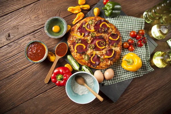 Pizza en ingrediënten op tafel — Stockfoto