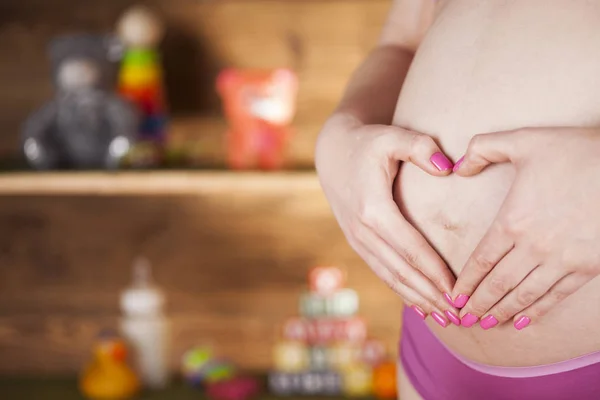 Беременная женщина с сердечным знаком — стоковое фото