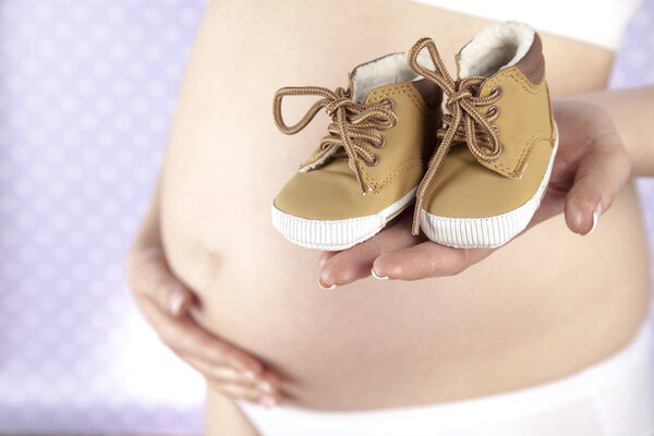 Pregnant woman holding baby shoes 