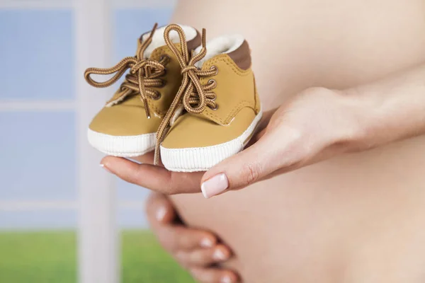 Беременная женщина держит детские туфли — стоковое фото
