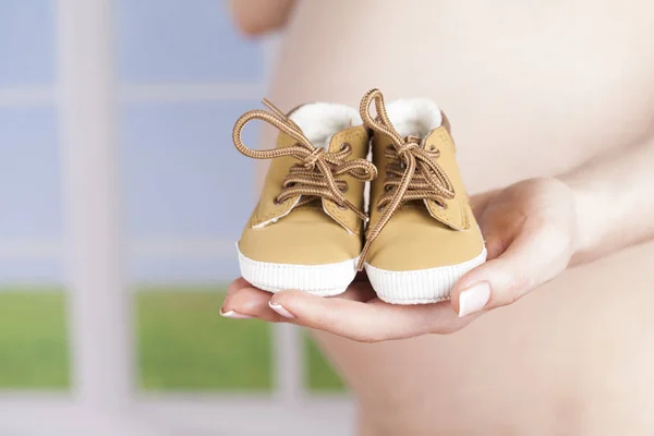 Pregnant woman holding baby shoes — Stock Photo, Image