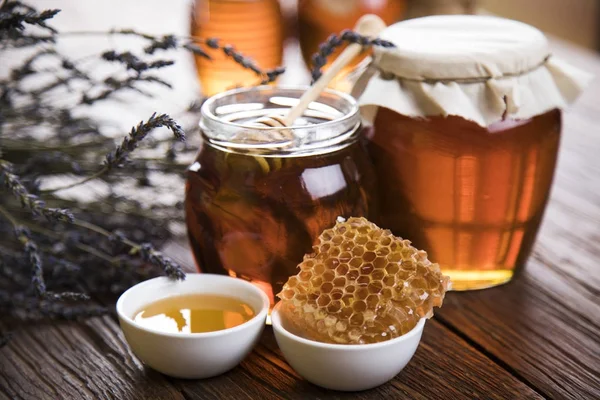 Honey jar with dipper and flowing honey — Stock Photo, Image