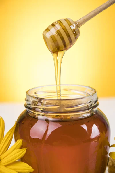 Honey and wooden stick are on a table — Stock Photo, Image