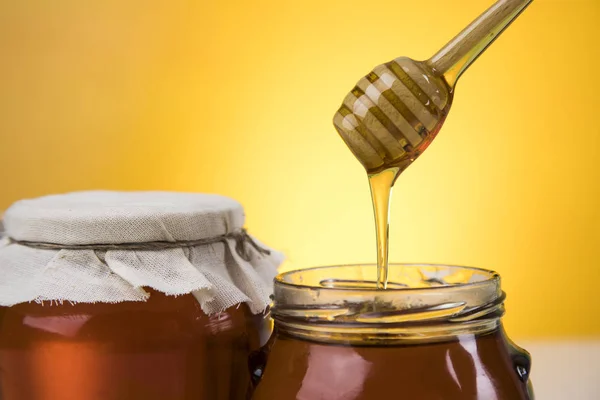 Honey and wooden stick are on a table — Stock Photo, Image