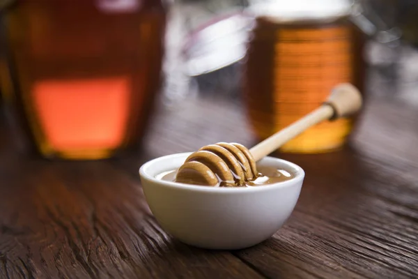 Honey jar with dipper and flowing honey — Stock Photo, Image