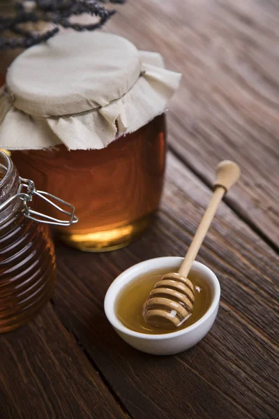 Honey jar with dipper and flowing honey — Stock Photo, Image