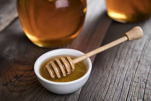 Honey jar with dipper and flowing honey — Stock Photo, Image