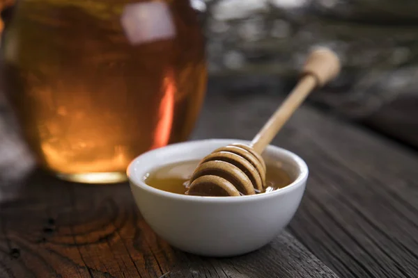 Honey jar with dipper and flowing honey — Stock Photo, Image