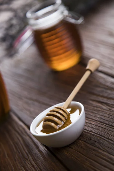 Honey jar with dipper and flowing honey — Stock Photo, Image