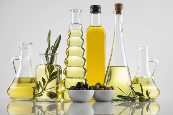 Bottiglie di olio d'oliva, ramo d'oliva e oli da cucina — Foto Stock