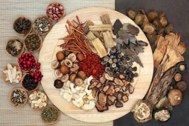 Chinese  herbs & spice used in traditional herbal medicine on a wooden board, bamboo & lokta paper. Flat lay clipart