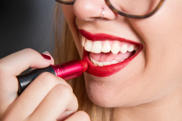 Chica sonriente puso el lápiz labial en los labios — Foto de Stock