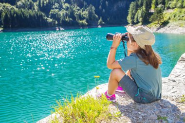 Kız panorama dürbünle izliyor.