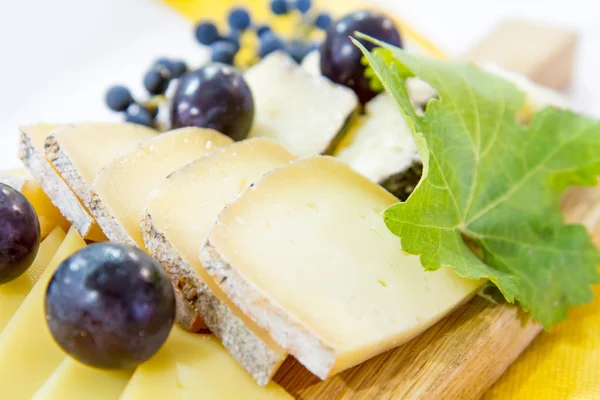 Platter of cheese and black grapes — Stockfoto