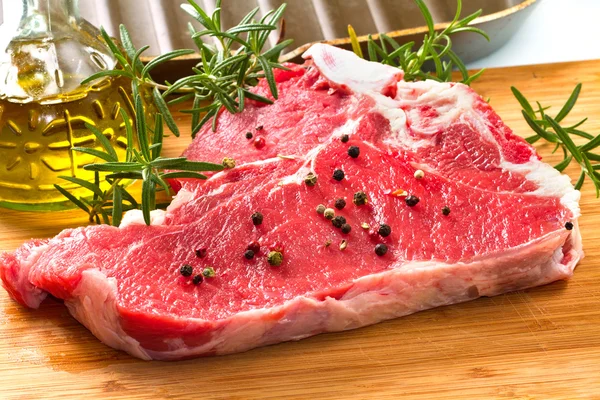 Красное мясо с розмарином на столе — стоковое фото