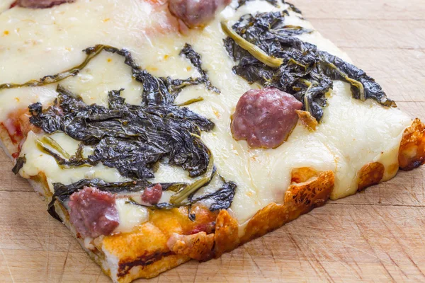 Piece of pizza with sausage and spinach — Stock Photo, Image