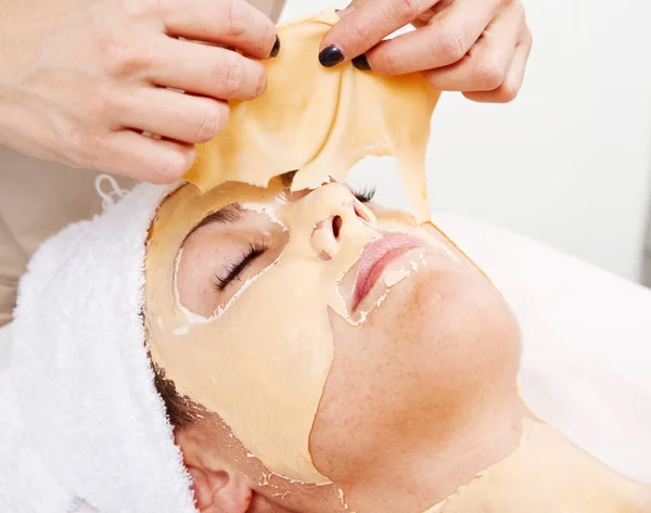 Mooie jonge vrouw in een schoonheidscentrum gezichts masker verwijderen — Stockfoto