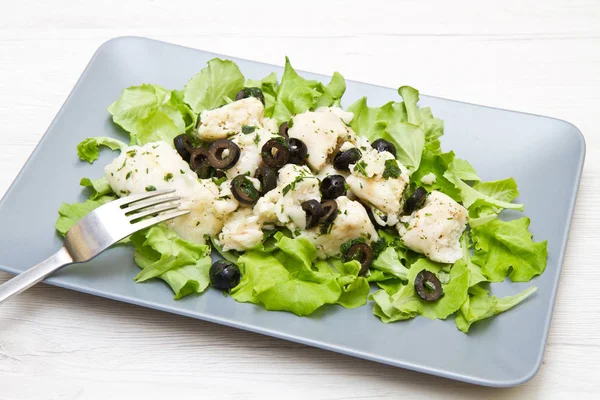 Prato de salada de bacalhau com azeitonas pretas — Fotografia de Stock